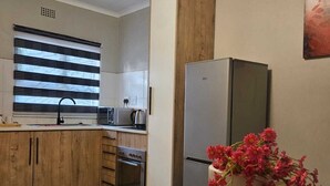 Una cocina moderna con armarios de madera, un refrigerador de acero inoxidable y un florero con flores rosadas en la encimera.