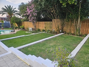 Un patio trasero con piscina, cerco de madera y césped bien cuidado.