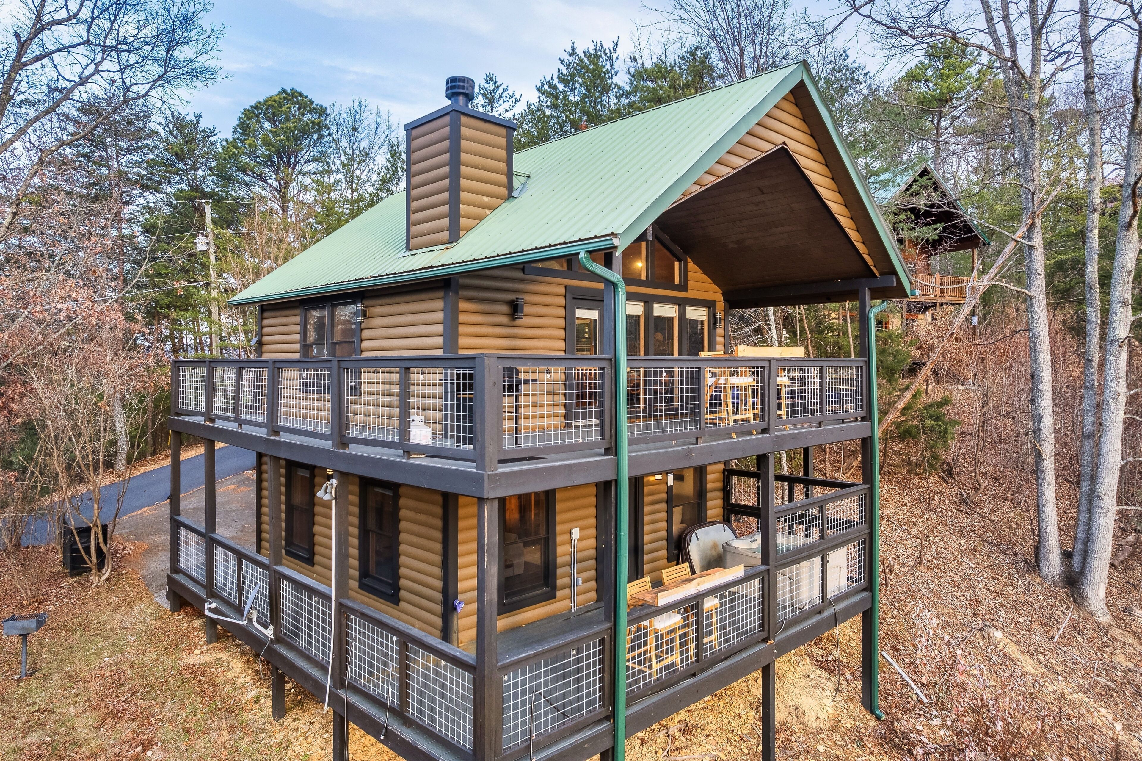 A two-story log cabin with a balcony, surrounded by trees.
