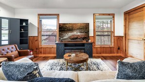Una sala de estar con chimenea, sofá, una mesa de centro y un cuadro grande.