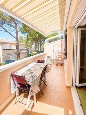 A balcony with a table and chairs, a sliding door, and a view of the neighborhood. - EUREKA C43 - Appartement - Piscine - 100m Plages (Agde)
