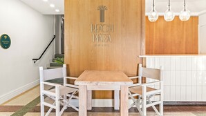 Een houten scheidingswand met de aanduiding 'Beach Plaza Hotel', een houten tafel met twee stoelen, een trap en een bordje voor de toiletten.
