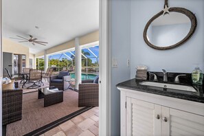 A bathroom with a round mirror, a sink, and a ceiling fan. - Triple Palms Vacation Home, With Heated Pool (Cape Coral)