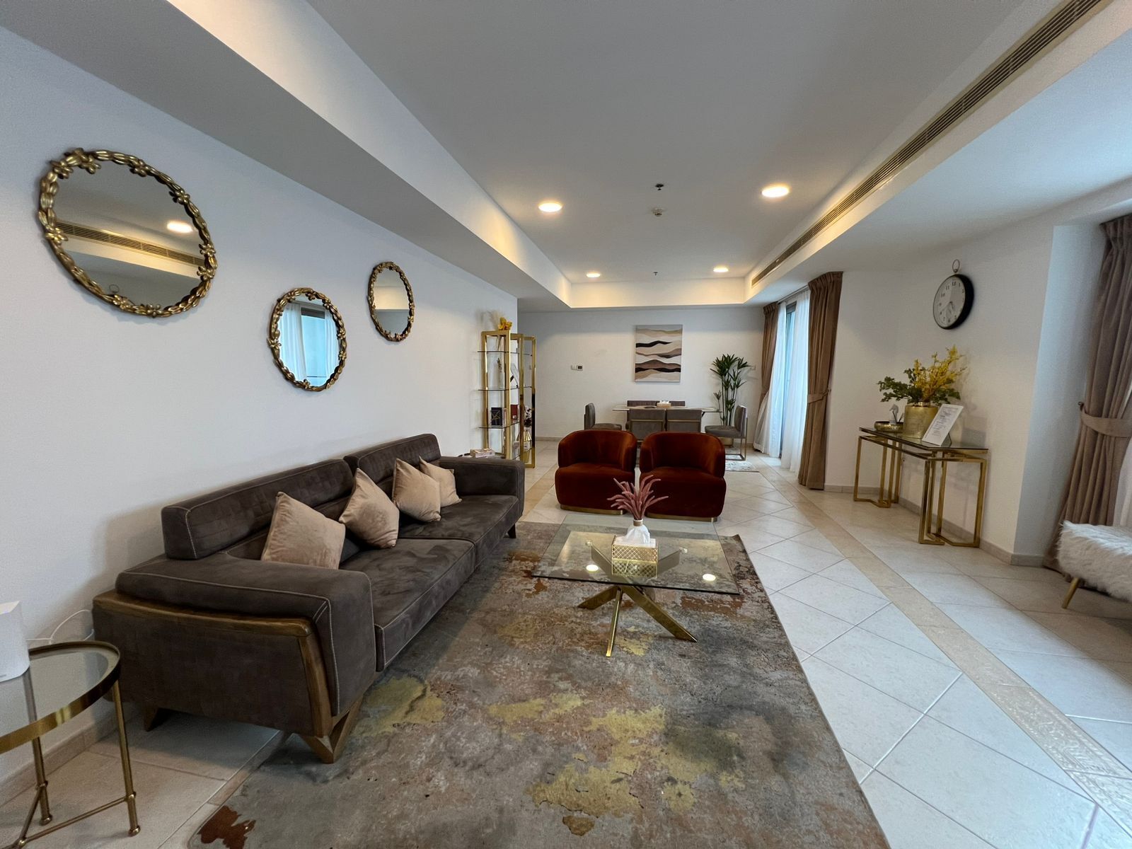 Un salon moderne comprenant un canapé, des fauteuils, une table basse et des miroirs décoratifs.