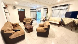 A living room with a sofa, armchairs, a coffee table, a TV, and a door leading to another room. - Peaceful 3BR Villa | Fast Starlink WiFi | Walk to Beach (Ahangama)