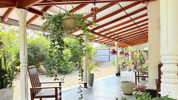 A covered patio area with wooden beams, potted plants, and a seating arrangement. - Peaceful 3BR Villa | Fast Starlink WiFi | Walk to Beach (Ahangama)