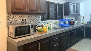A kitchen with dark cabinets, a microwave, a coffee maker, and a fruit bowl. - Peaceful 3BR Villa | Fast Starlink WiFi | Walk to Beach (Ahangama)