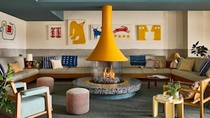 Una sala moderna con chimenea central, sofás y una mesa de centro.