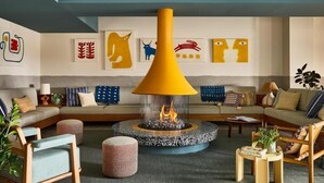 A modern living room with a central fireplace, sofas, and a coffee table. - Wayfinder Suite | Wayfinder Newport | Newport Unfiltered, Mural Pool | 2 Units (Newport County)