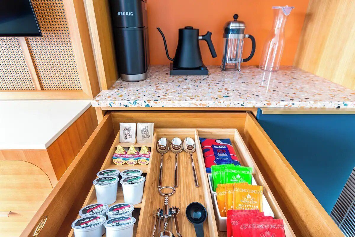Una cocina con cafetera, hervidor y cafeteras sobre la encimera.