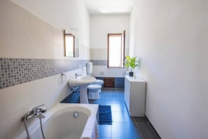 Un baño moderno con bañera, dos lavamanos, inodoro y ventana.