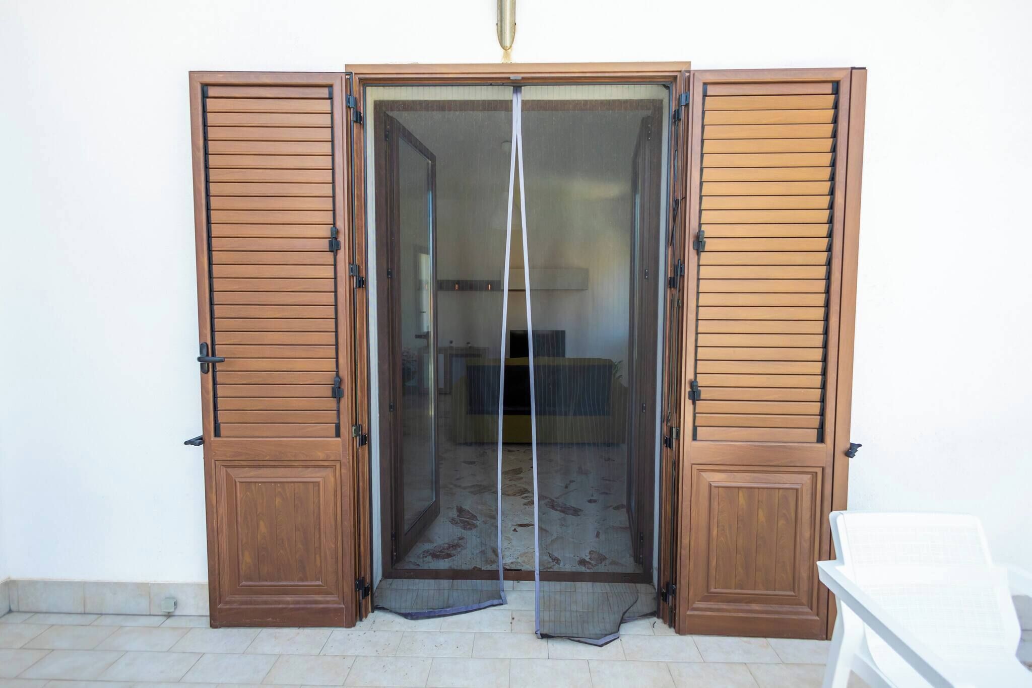 A room with a sliding door, a chair, and a bed.