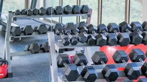 Et fitnesscenter med træningsudstyr, herunder håndvægte og løbebånd.