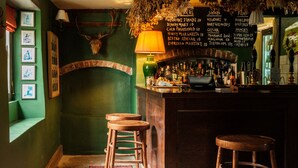 A bar area with stools, a bar counter, and a menu board. - The Bell & Crown (Zeals)