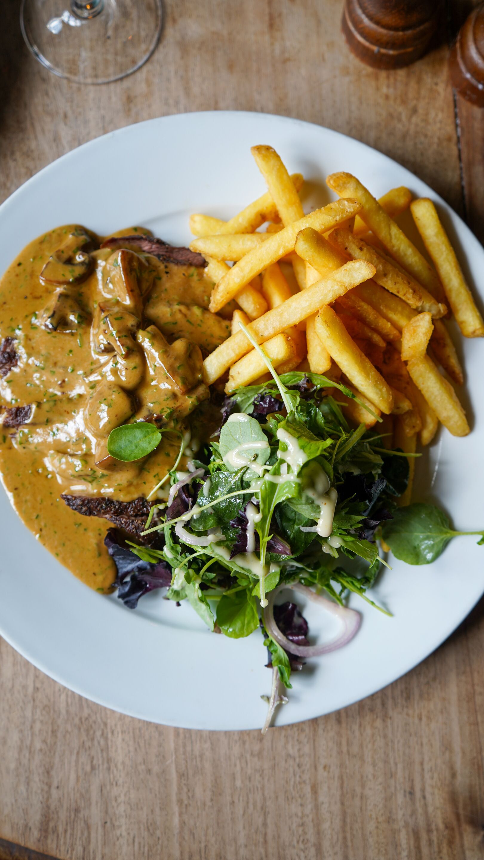 Un plato con bistec, papas fritas y ensalada.