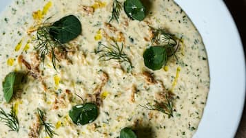 Un plato blanco con crema de sopa adornada con eneldo y rodajas de limón.