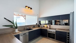 Una cucina moderna con lavastoviglie integrata, un lavello e una finestra con vista su un balcone.