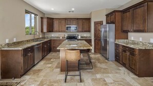A modern kitchen with granite countertops, stainless steel appliances, and dark wooden cabinets. - Ranch Road Desert Oasis...Privacy...Unbelievable Mountain Views! (Scottsdale)