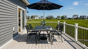 Eine Terrasse mit Tisch, Stühlen und Sonnenschirm, mit Blick auf Häuser in der Ferne.