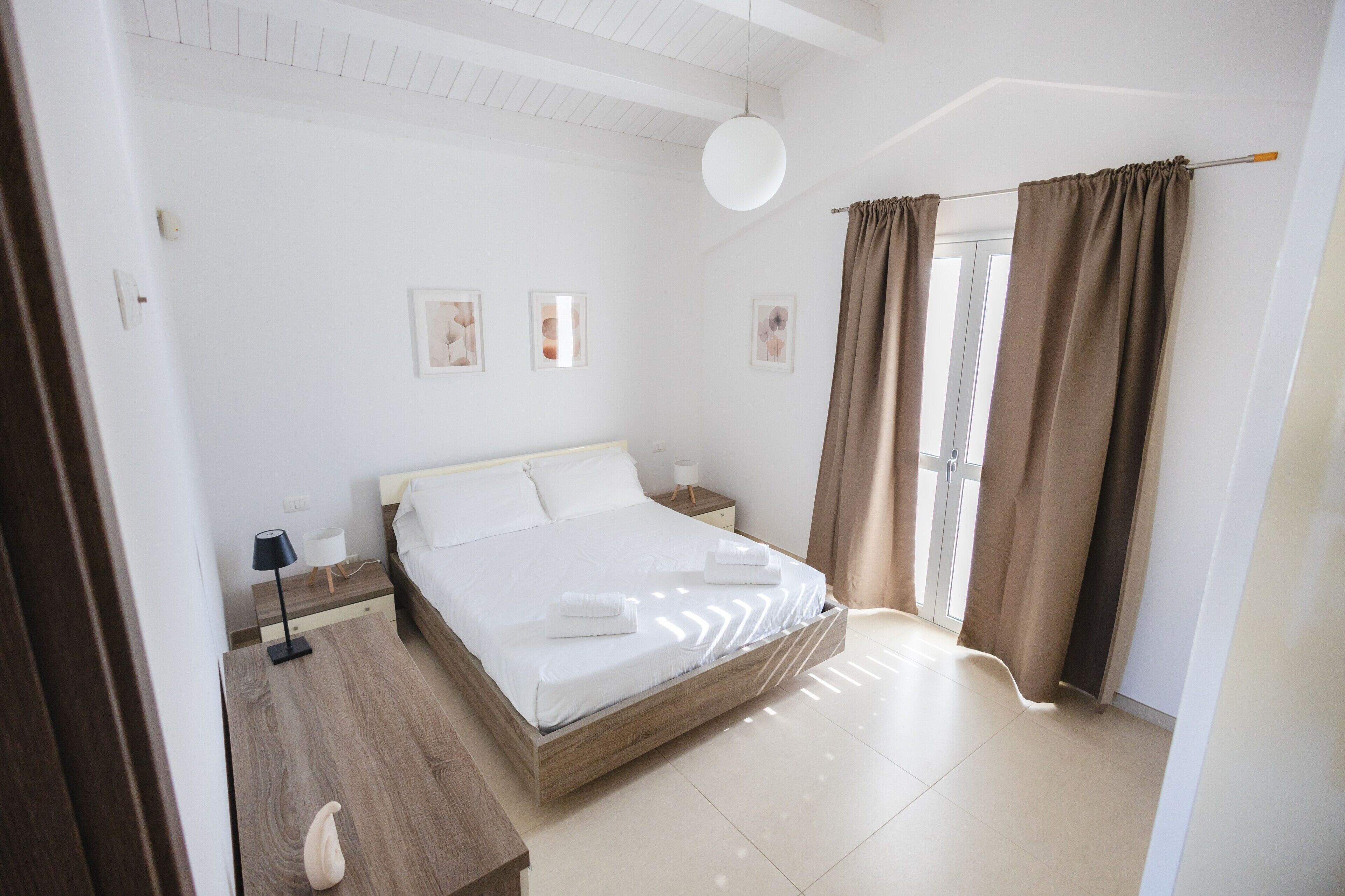 A bedroom with a bed, bedside tables, a lamp, and curtains.