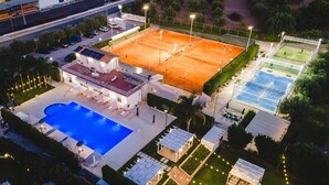 Ein Tennisplatz im Freien, ein Schwimmbecken und eine überdachte Sitzgelegenheit.