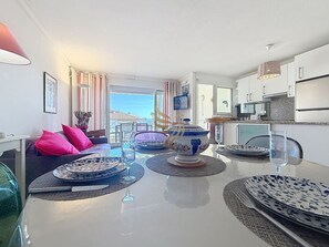 A modern kitchen with a dining area, a large window, and a view of the outdoors. - Le Panorama Hermes T3 - Sea view - Terrace WIFI (Fréjus)