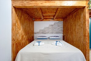 Ein Zimmer aus Holz mit einem Bett, zwei Kissen und einer Wand mit geometrischem Muster.