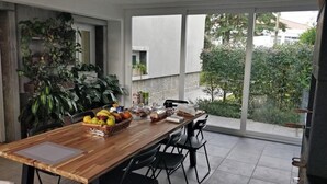 A dining area with a wooden table, black chairs, and a view of greenery outside. - Casa Jasmim - Tranquil Refuge (Algueirão-Mem Martins)