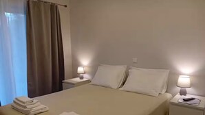 A hotel room with a bed, two bedside tables, a lamp on each table, and a window with curtains. - Casa Jasmim - Tranquil Refuge (Algueirão-Mem Martins)