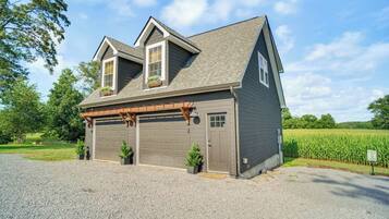 A two-story house with a garage, a covered porch, and a gravel driveway.