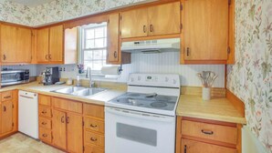 A kitchen with wooden cabinets, a microwave, a stove, and a sink. - Little Farm House with Shaded Front Porch, Fire Pit, Covered Parking (Cross Plains)