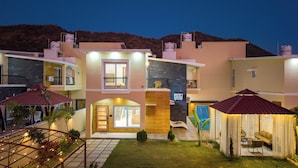 Um edifício residencial com vários andares, varandas, piscina e um jardim bem cuidado.