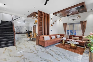 Un saló modern amb terra de marbre, un sofà, una zona de menjador i una escala.