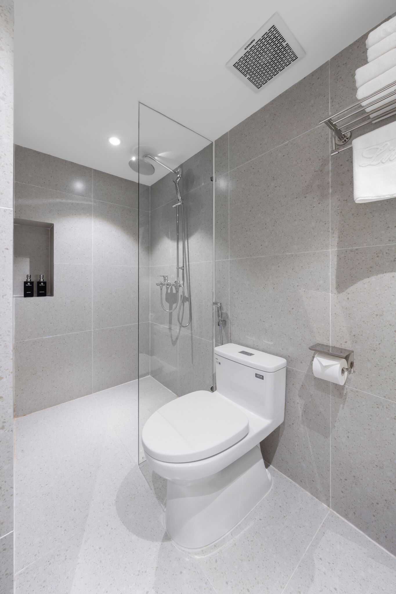 A modern bathroom with a glass-enclosed shower, a toilet, and a towel rack.