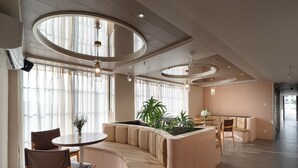 Un intérieur moderne avec un espace salon aux lignes courbes, une table ronde et une plante en pot.