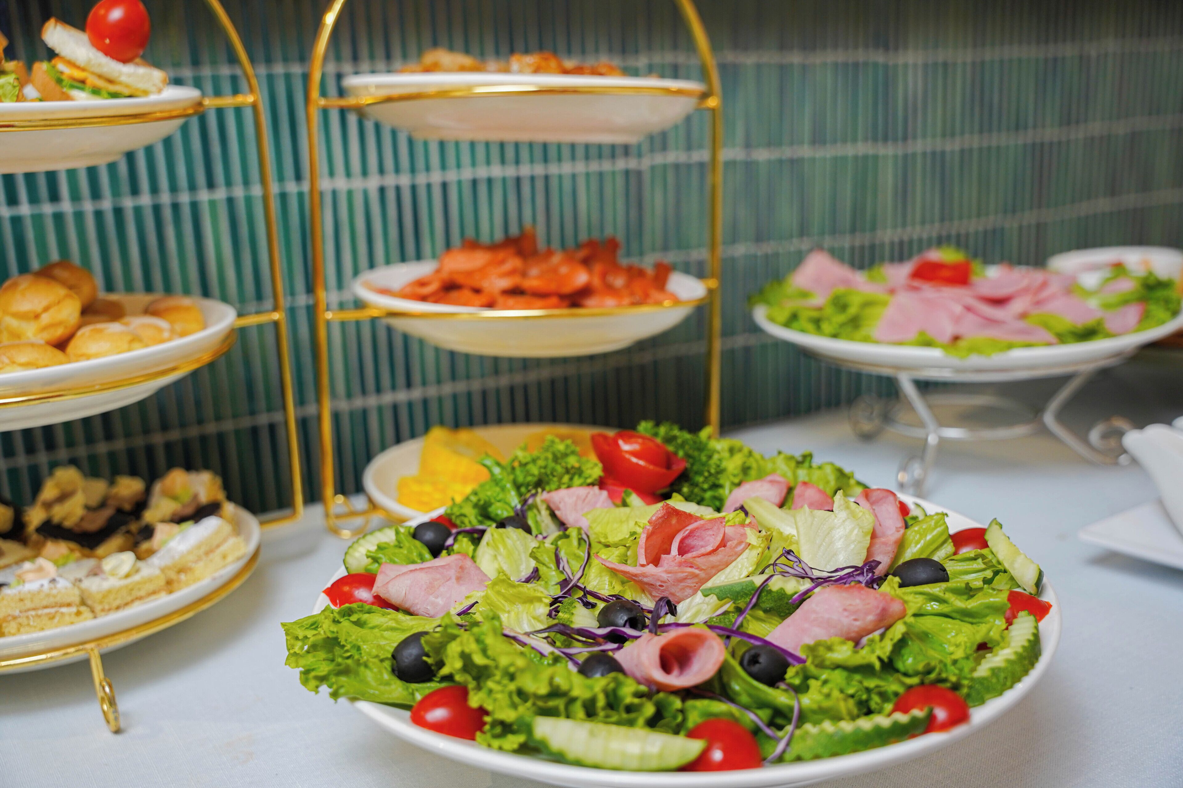En buffet med forskellige retter, heriblandt salater, sandwiches og andre madvarer.