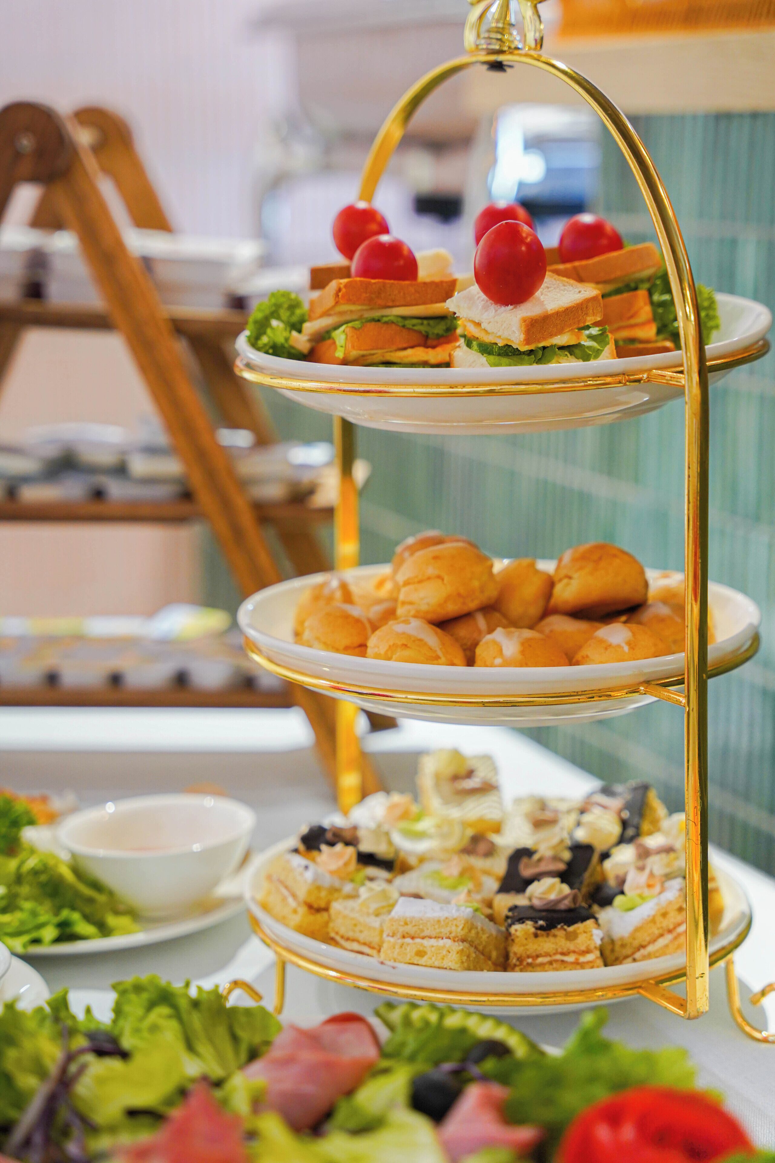 A three-tiered dessert stand with various pastries and sandwiches.
