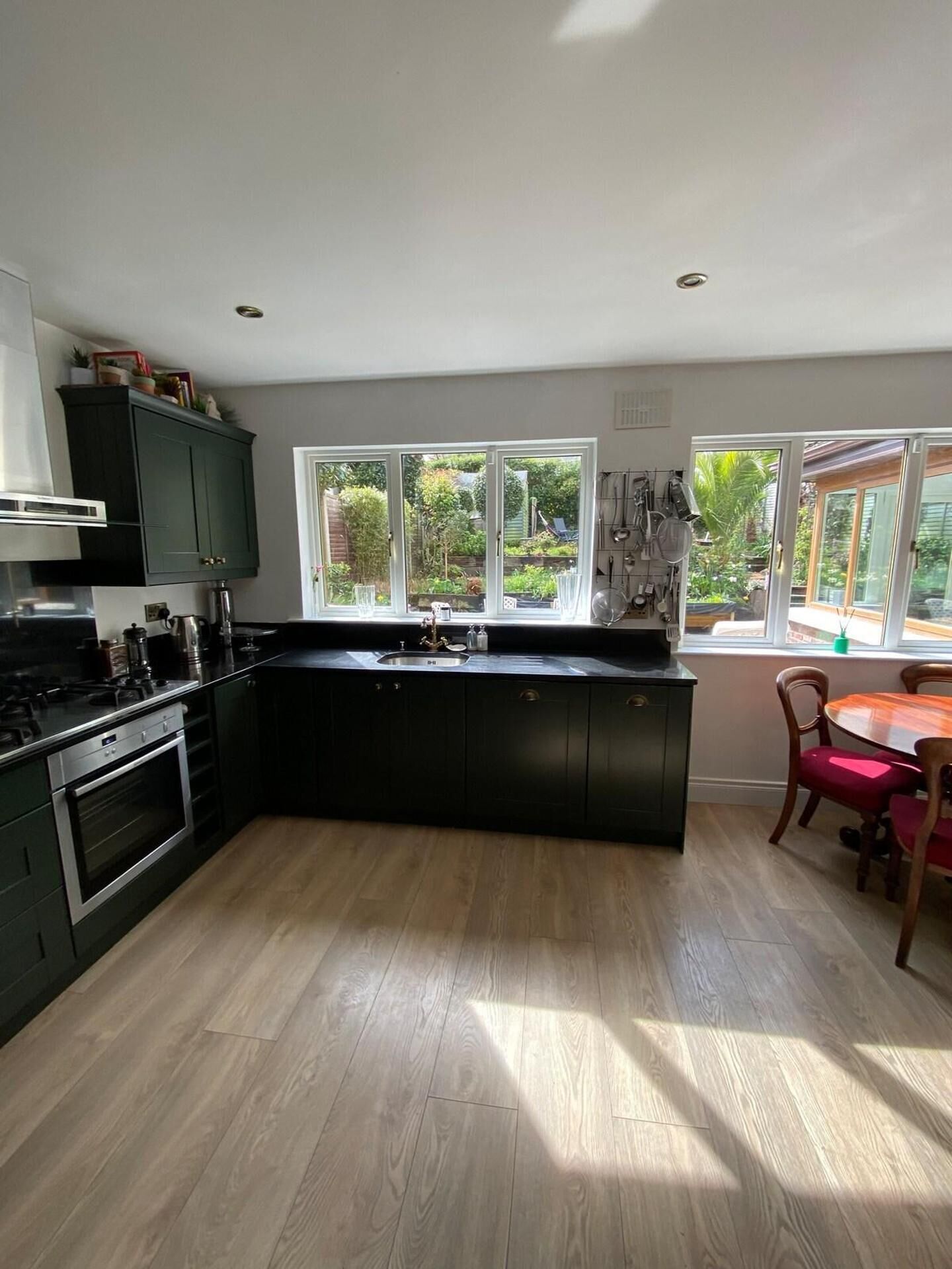 A modern kitchen with a central island, built-in appliances, and a view of the garden through large windows.