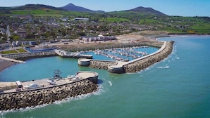 A coastal marina with boats, a stone breakwater, and a town in the background.