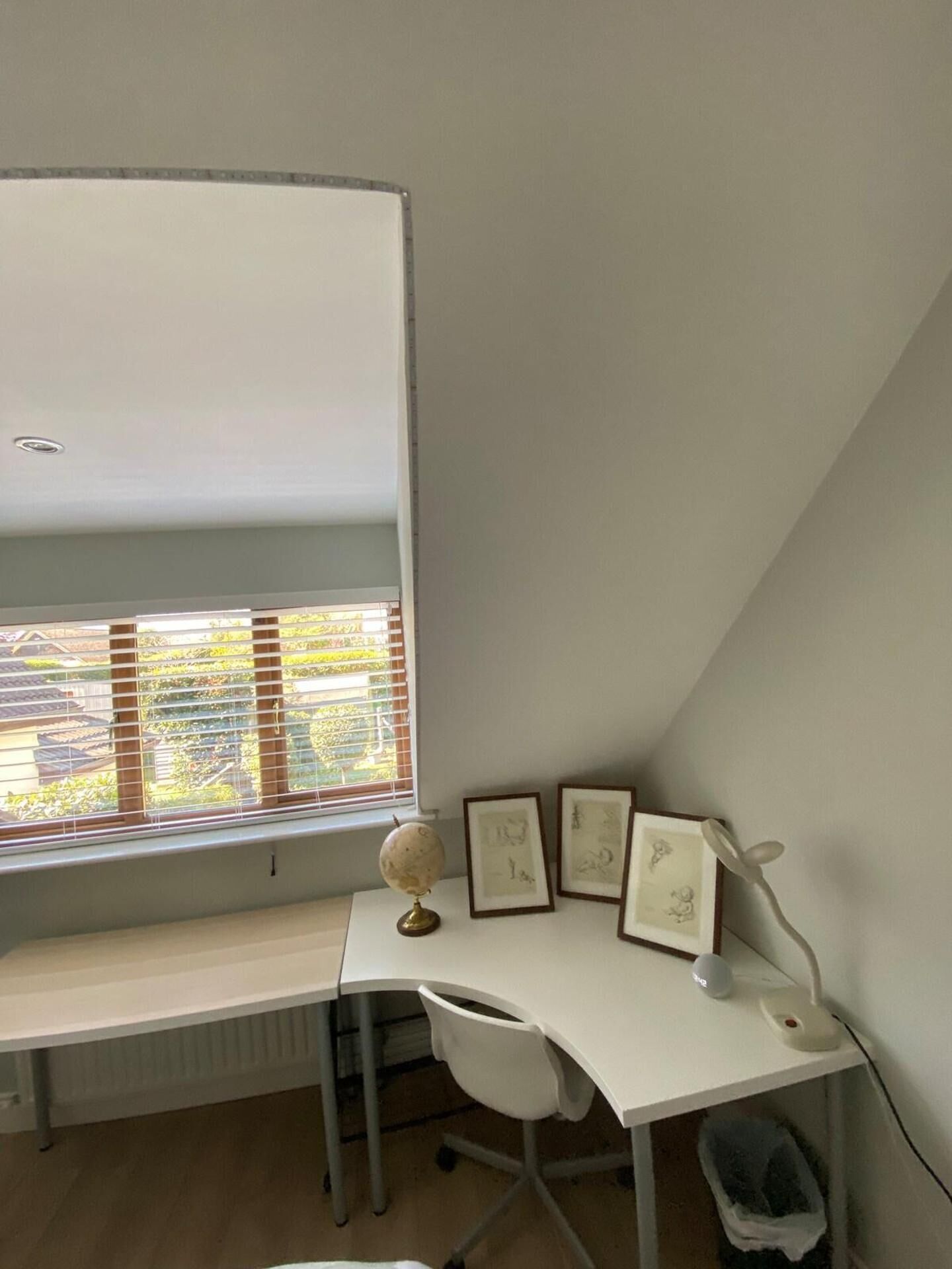 Ein Zimmer mit einem weißen Schreibtisch, einem Globus und gerahmten Bildern.