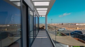 Un balcón con vista a un estacionamiento y un paisaje lejano.