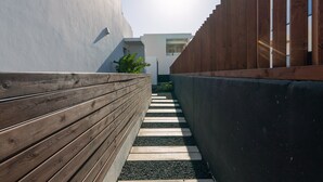 Un sendero estrecho bordeado por cercas de madera y un edificio moderno con fachada blanca.