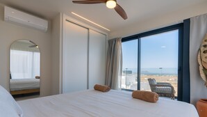 Habitación de hotel con cama, ventilador de techo, ventana grande con vistas y aire acondicionado de pared.