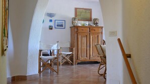Un couloir avec une porte en arc donnant sur une salle à manger meublée de meubles en bois et comprenant un buffet.