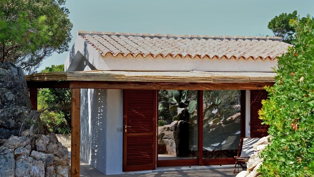 Un bâtiment moderne doté d’un toit en tuiles, de grandes portes vitrées et d’une terrasse en bois.