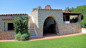 Un bâtiment en pierre avec un toit en tuiles, un escalier menant à l’entrée et un petit jardin.
