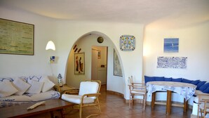 Un salon comprenant un canapé, des fauteuils, une table et un coin repas.