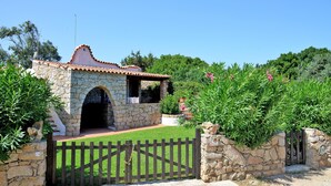 Un bâtiment en pierre avec un toit en tuiles, une porte en bois et un jardin bien entretenu.