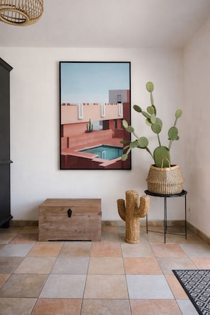 Ein Zimmer mit einem gerahmten Kunstwerk, einer Kakteenpflanze, einem gewebten Korb und einer Holzschatulle.