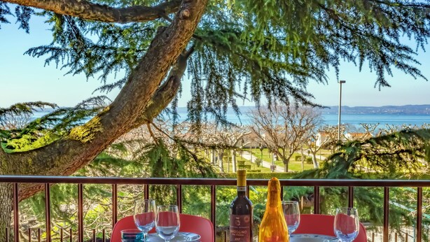 A table set for dining with a view of the sea and trees. - Large apartment with lake view terrace 5 minutes walk from the center (Bardolino)
